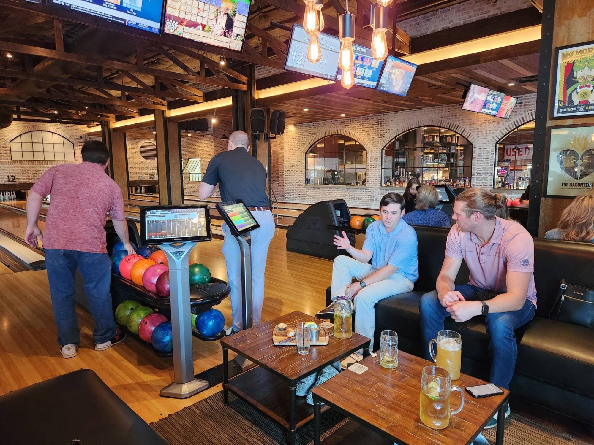 Team members enjoying drinks and conversation in the bowling alley lounge area between frames