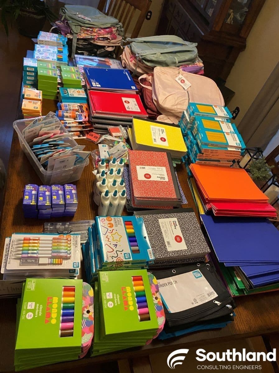 School supplies organized on the Southland conference table — markers, glue sticks, notebooks, pencils, and folders ready for distribution